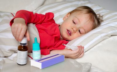 Criança na cama com termómetro, doente com escarlatina.